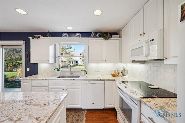 kitchen featuring white appliances, plenty of natural light, dark wood-style flooring, and a sink