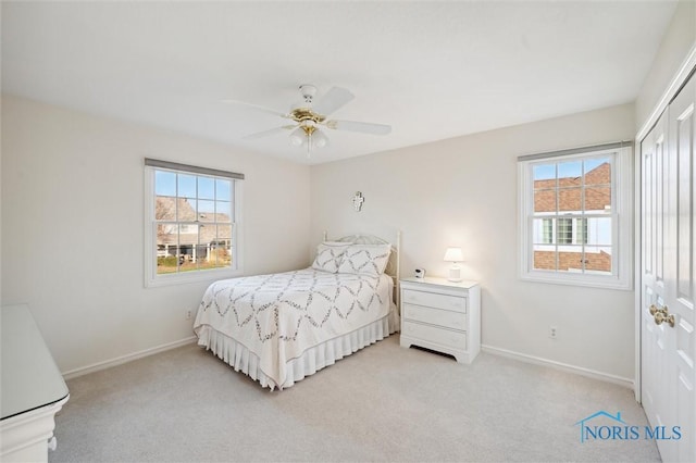 bedroom featuring baseboards, light carpet, and multiple windows