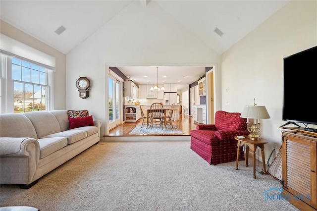 living area featuring a chandelier, high vaulted ceiling, and light carpet