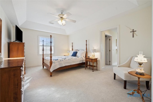 bedroom featuring visible vents, baseboards, light colored carpet, and a tray ceiling