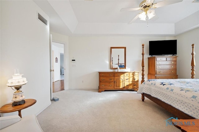 bedroom with ceiling fan, a raised ceiling, visible vents, baseboards, and carpet floors