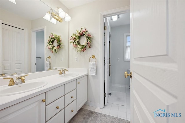 bathroom with baseboards, tile patterned flooring, double vanity, and a sink