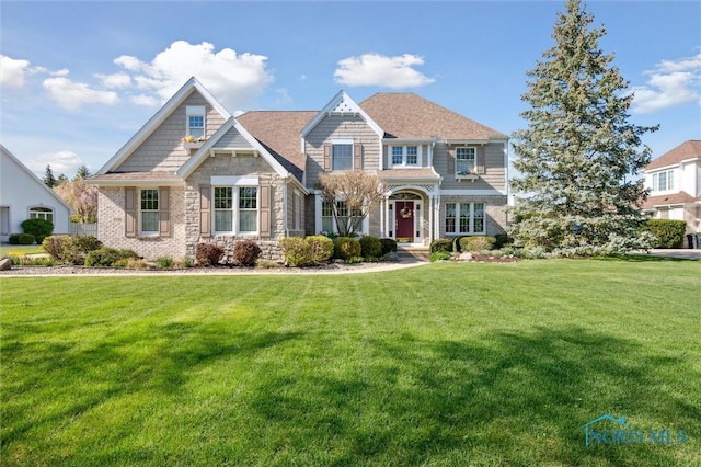 craftsman-style home with a front yard and stone siding