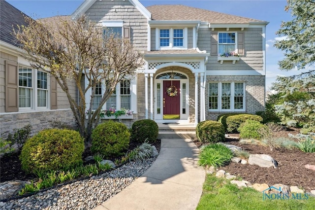 view of front of property featuring stone siding and roof with shingles