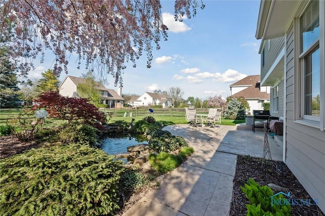 view of yard featuring outdoor dining space, a garden pond, and a patio