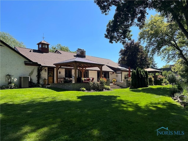 back of house featuring a gazebo, a yard, central AC unit, and a chimney