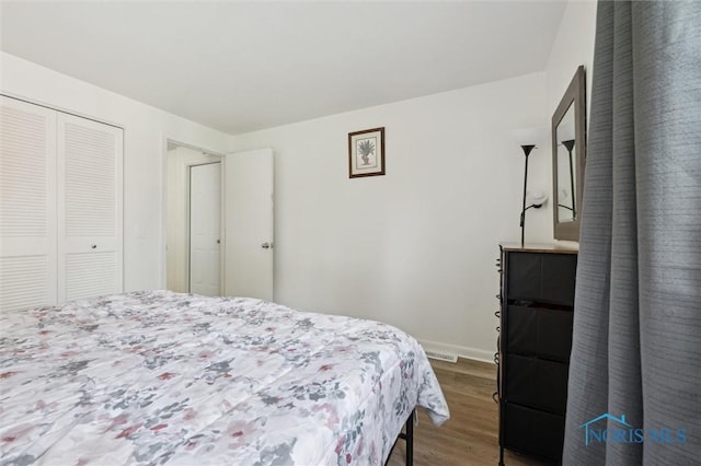 bedroom featuring a closet, baseboards, and wood finished floors