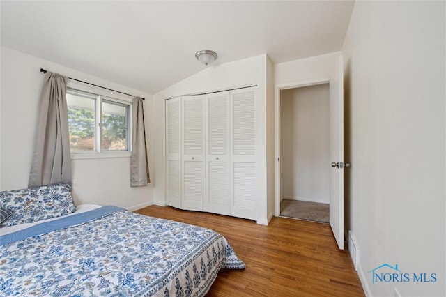 bedroom featuring a closet, baseboards, vaulted ceiling, and wood finished floors