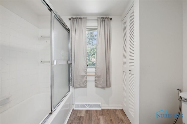bathroom featuring visible vents, wood finished floors, baseboards, a closet, and shower / bath combination with glass door