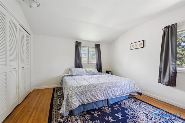 bedroom featuring a closet, baseboards, vaulted ceiling, and wood finished floors