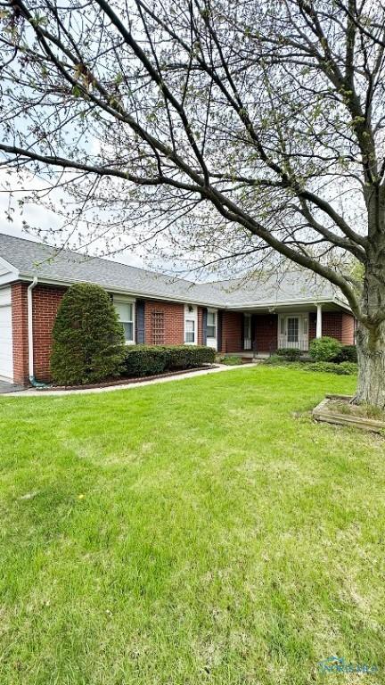 ranch-style house featuring brick siding, a front lawn, and an attached garage