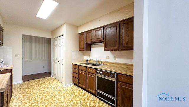 kitchen with a sink, dishwasher, backsplash, and light countertops