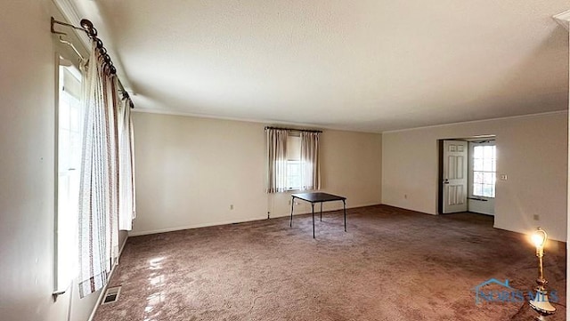 carpeted empty room featuring visible vents and crown molding