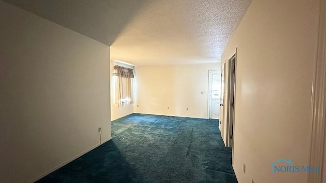 empty room featuring dark carpet and a textured ceiling