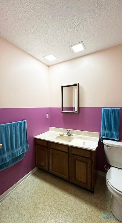 bathroom with toilet, a textured ceiling, and vanity