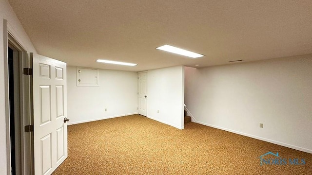 finished basement with stairs, a textured ceiling, carpet floors, and baseboards