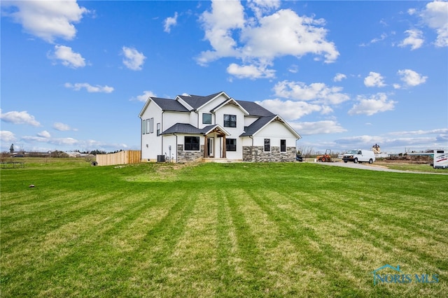 view of front facade with fence, a front yard, and stone siding