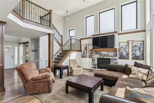 living room with a stone fireplace, visible vents, plenty of natural light, and wood finished floors
