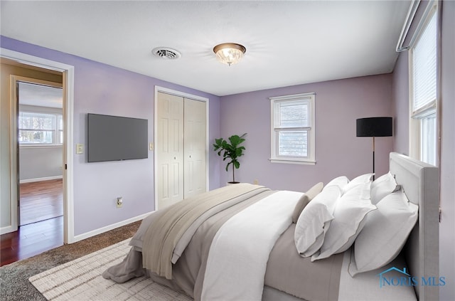 bedroom with baseboards, a closet, visible vents, and multiple windows
