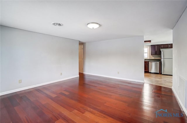 unfurnished living room with visible vents, baseboards, and wood finished floors