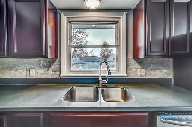 kitchen with a sink, dark countertops, dishwasher, and dark brown cabinets