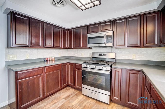 kitchen with visible vents, light wood finished floors, appliances with stainless steel finishes, and backsplash
