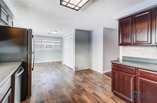 kitchen with baseboards, appliances with stainless steel finishes, reddish brown cabinets, and dark wood-style floors