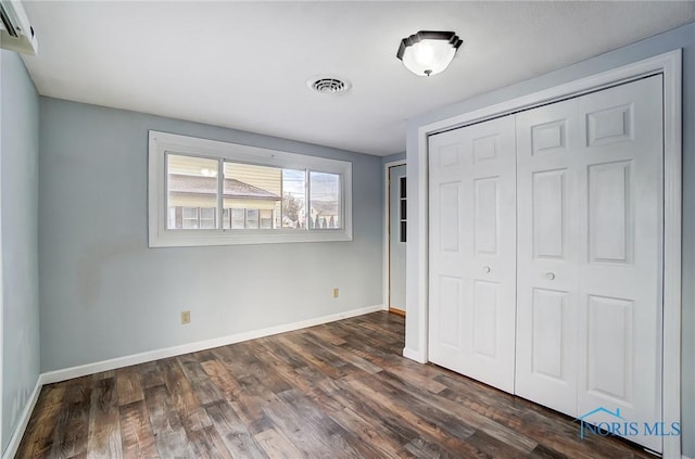 unfurnished bedroom featuring baseboards, a closet, and dark wood-style floors