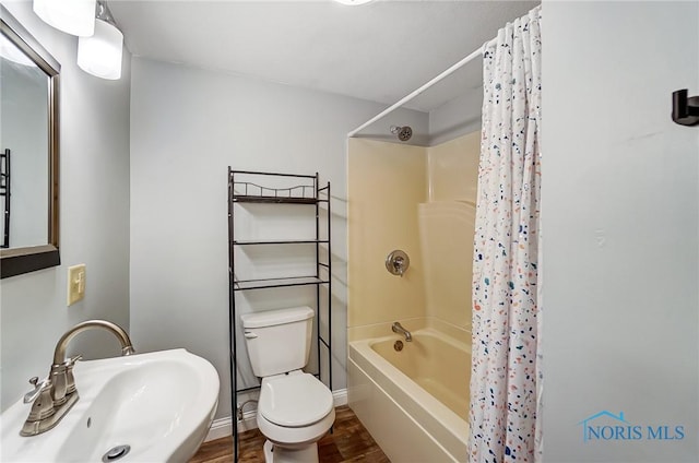 bathroom featuring a sink, shower / bath combo with shower curtain, toilet, baseboards, and wood finished floors