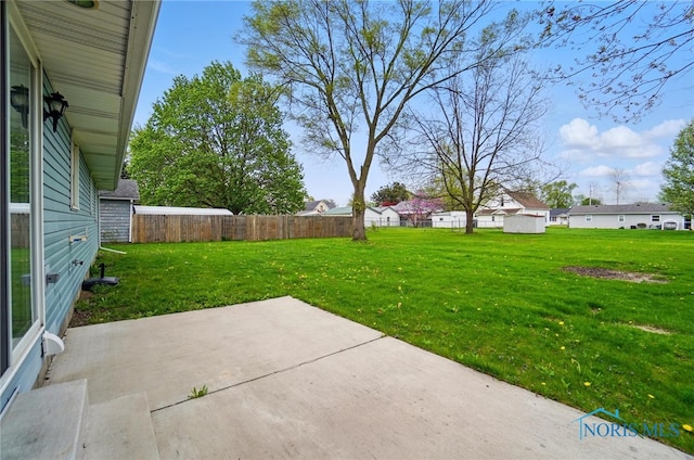 view of yard featuring fence, a residential view, and a patio area