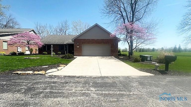 single story home featuring a front lawn, driveway, and a garage