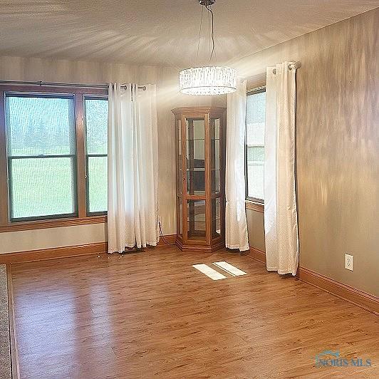 unfurnished dining area featuring wood finished floors and baseboards