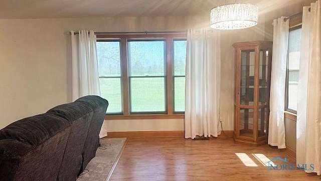 living area featuring baseboards, wood finished floors, and a notable chandelier