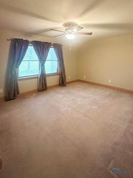 unfurnished room with ceiling fan, baseboards, and light carpet