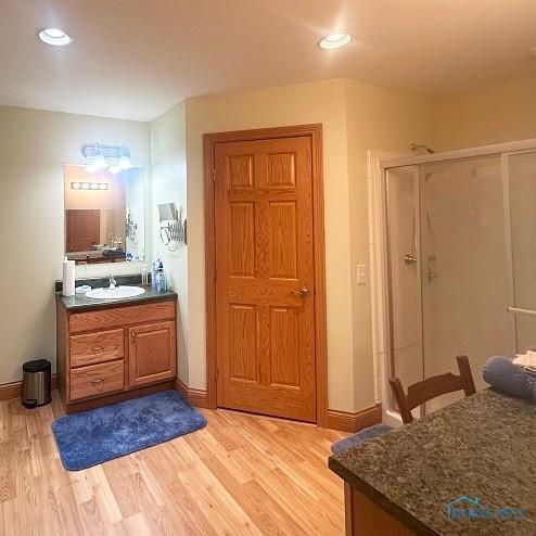 full bathroom featuring recessed lighting, wood finished floors, vanity, baseboards, and a stall shower