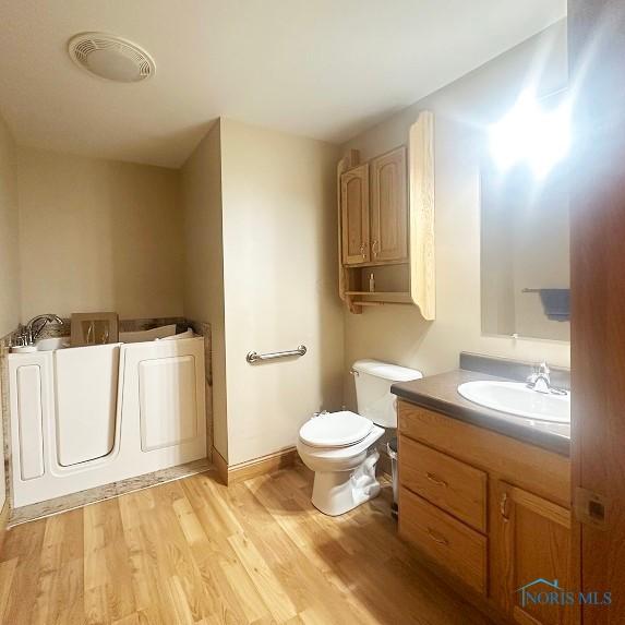 full bathroom featuring vanity, a bathtub, toilet, visible vents, and wood finished floors