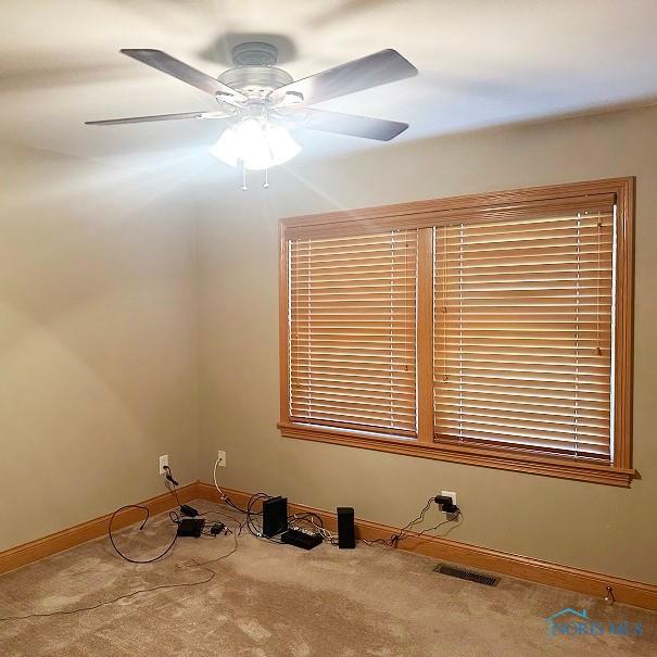 spare room with carpet, visible vents, a ceiling fan, and baseboards