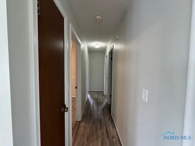 hall featuring baseboards and dark wood-style flooring