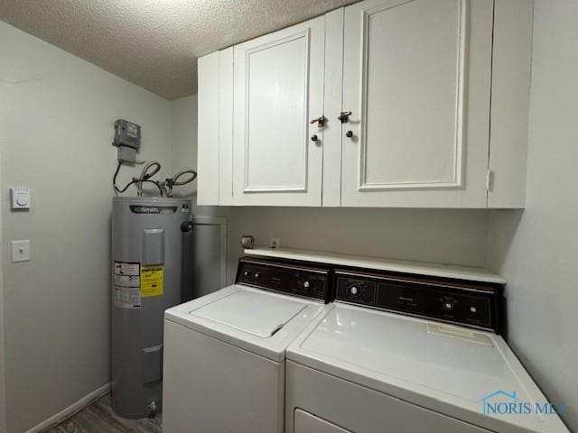 clothes washing area featuring a textured ceiling, washing machine and dryer, baseboards, electric water heater, and cabinet space