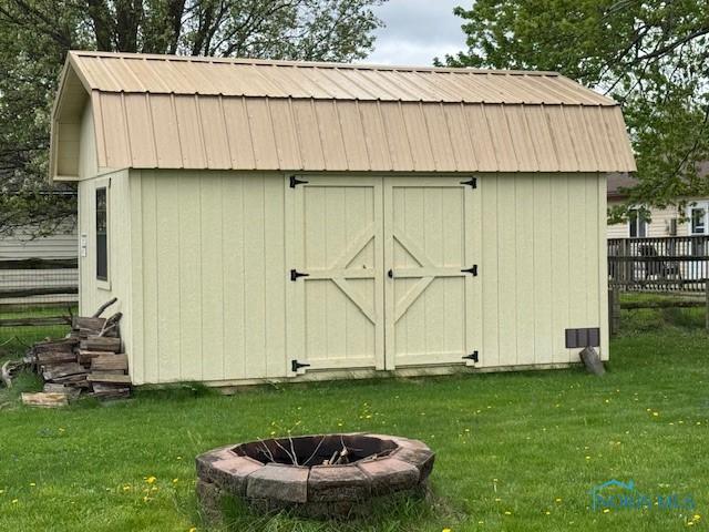 view of shed with fence and a fire pit