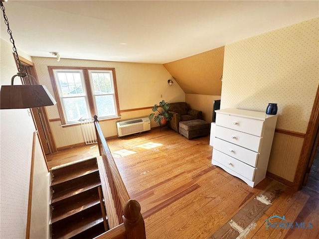 399 Melmore St, Tiffin, OH 44883 - interior space featuring an AC wall unit, wallpapered walls, vaulted ceiling, and wood finished floors