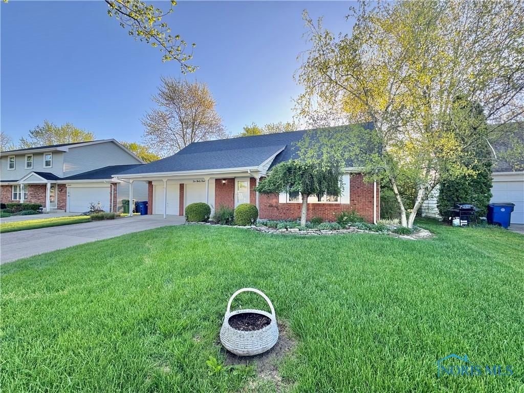 view of front of house featuring a garage, concrete driveway, a front yard, and brick siding