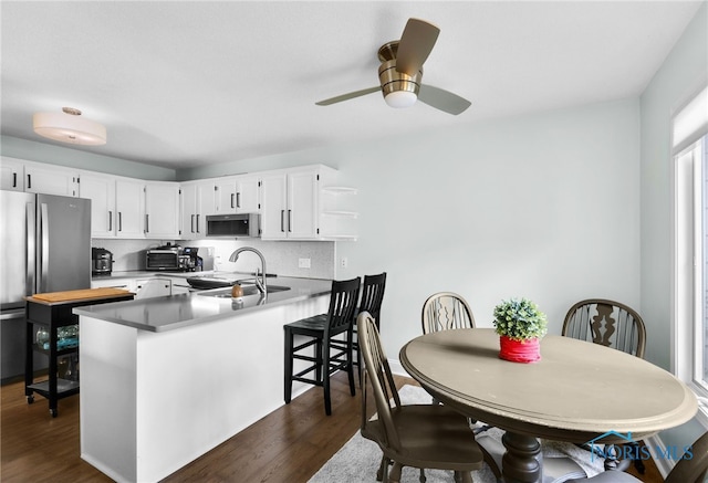 kitchen with white cabinetry, a sink, stainless steel appliances, dark wood finished floors, and a peninsula