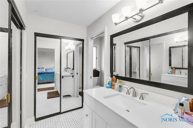 ensuite bathroom with tile patterned flooring, ensuite bath, a textured ceiling, and vanity