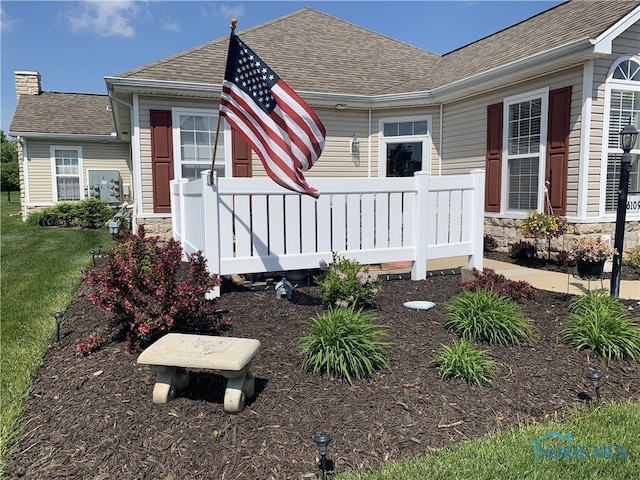 view of front of property featuring a shingled roof, a chimney, a front yard, and stone siding