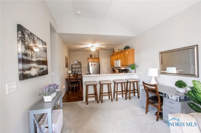 dining area featuring ceiling fan, vaulted ceiling, and light carpet