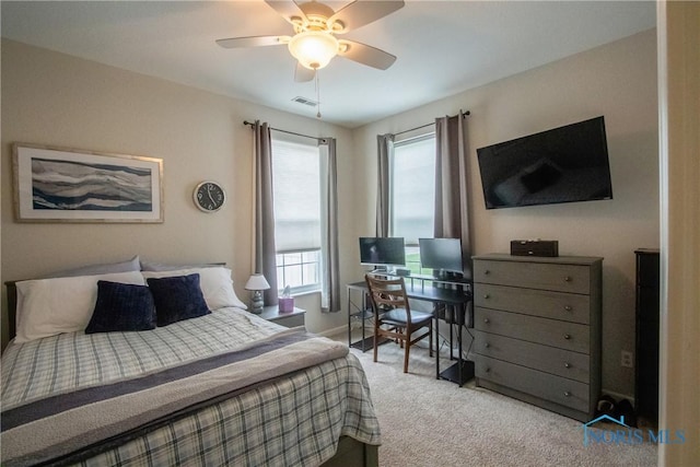 carpeted bedroom featuring ceiling fan, visible vents, and multiple windows