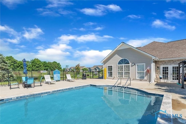 community pool featuring french doors, fence, and a patio