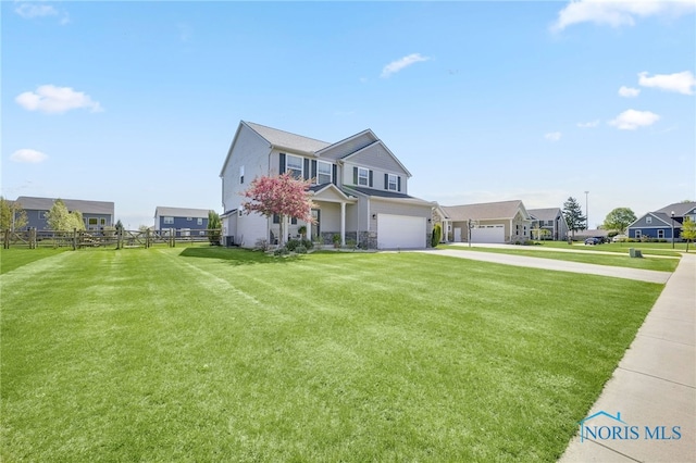 traditional-style home featuring fence, an attached garage, a front lawn, stone siding, and concrete driveway