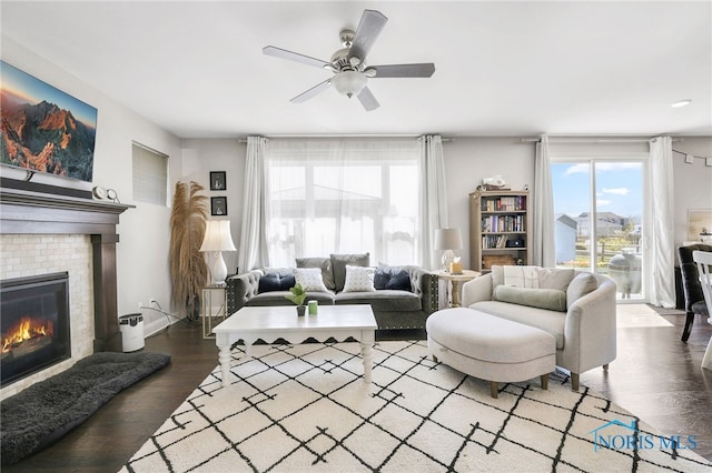 living area featuring plenty of natural light, ceiling fan, wood finished floors, and a fireplace